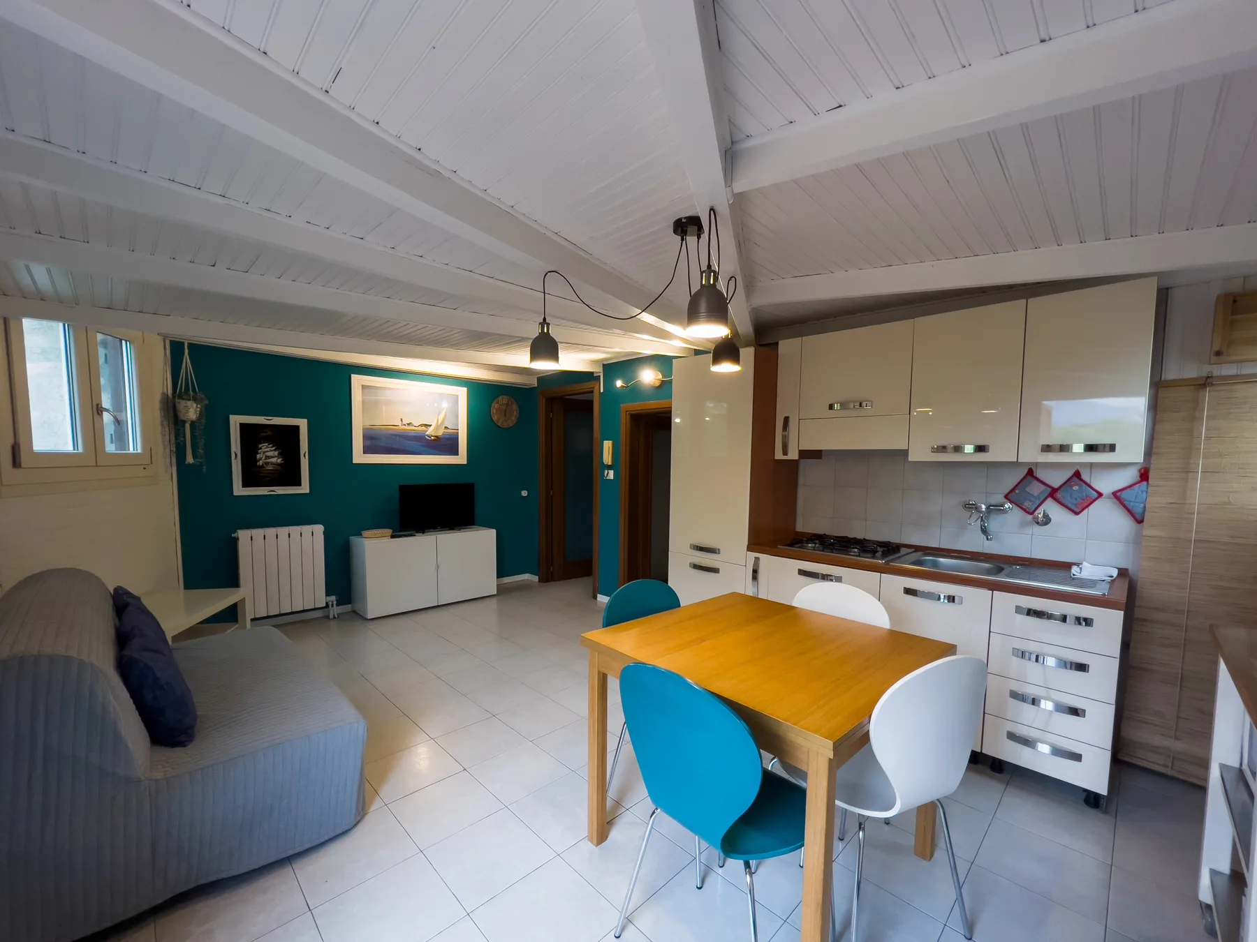 Sala de estar y cocina diáfanas con mesa de comedor y asientos.