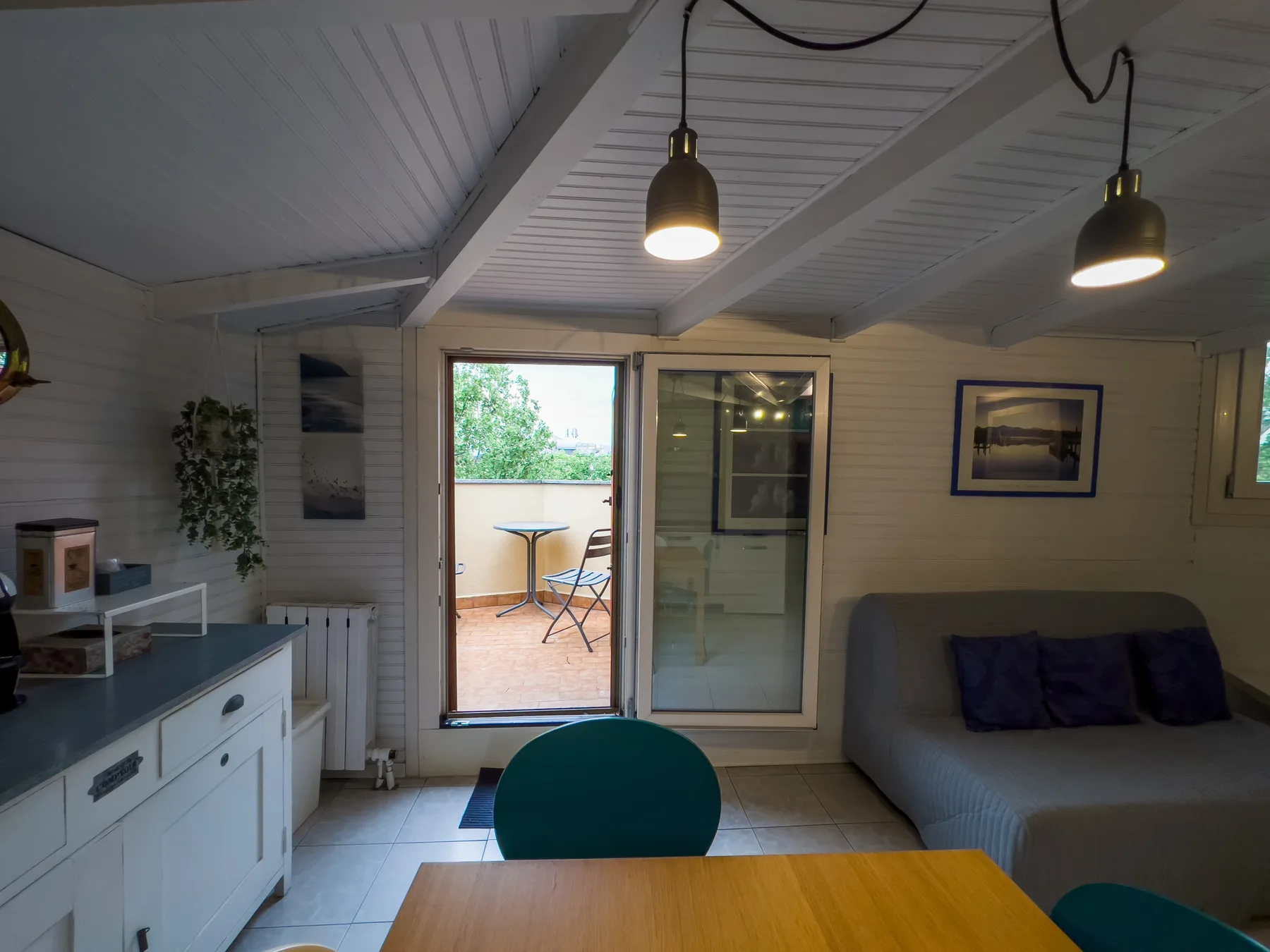 Una sala luminosa con mesa de comedor, sofá y puertas corredizas de vidrio hacia un patio.
