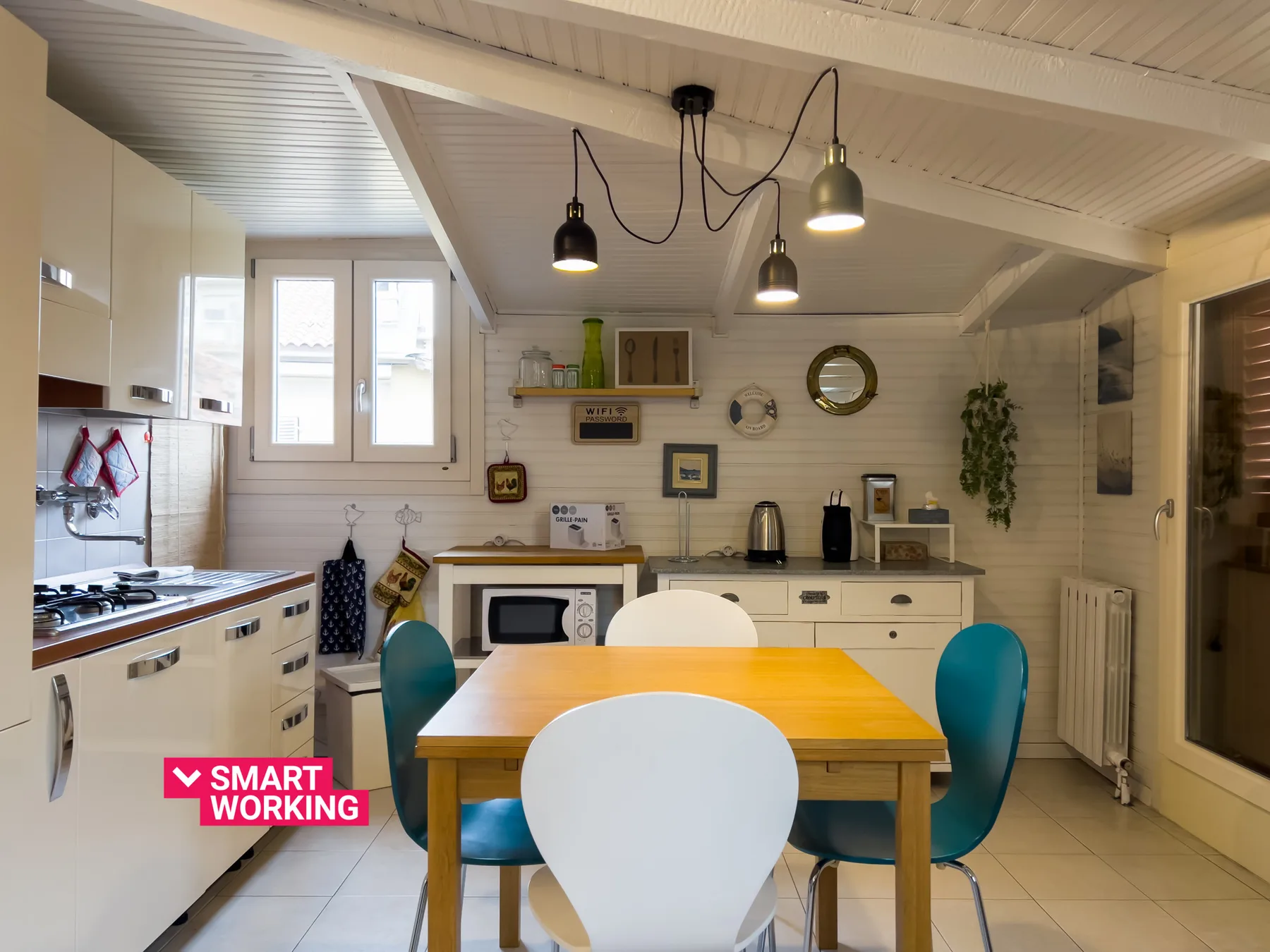 Una luminosa cocina con comedor, mesa de madera y gabinetes blancos.