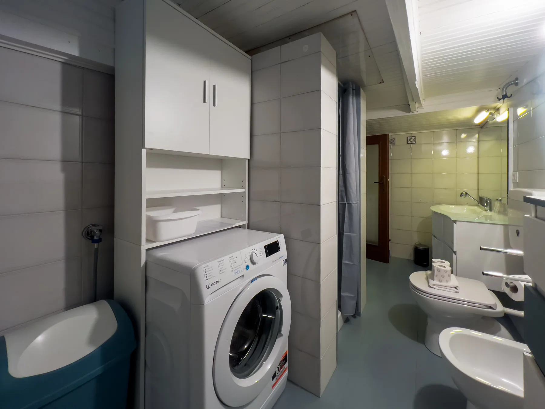 Un baño con azulejos, lavadora, lavabo y ducha.