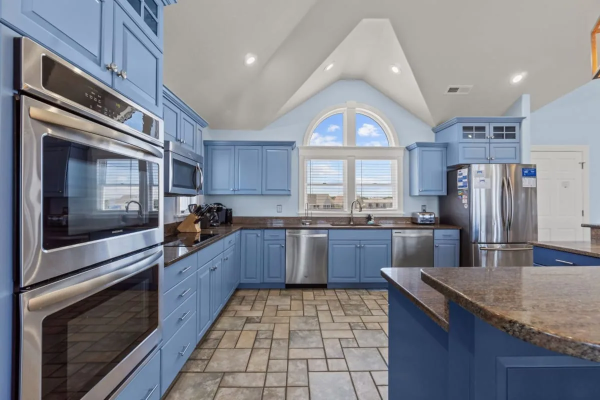A spacious kitchen with blue cabinets, stainless steel appliances, and a central island.