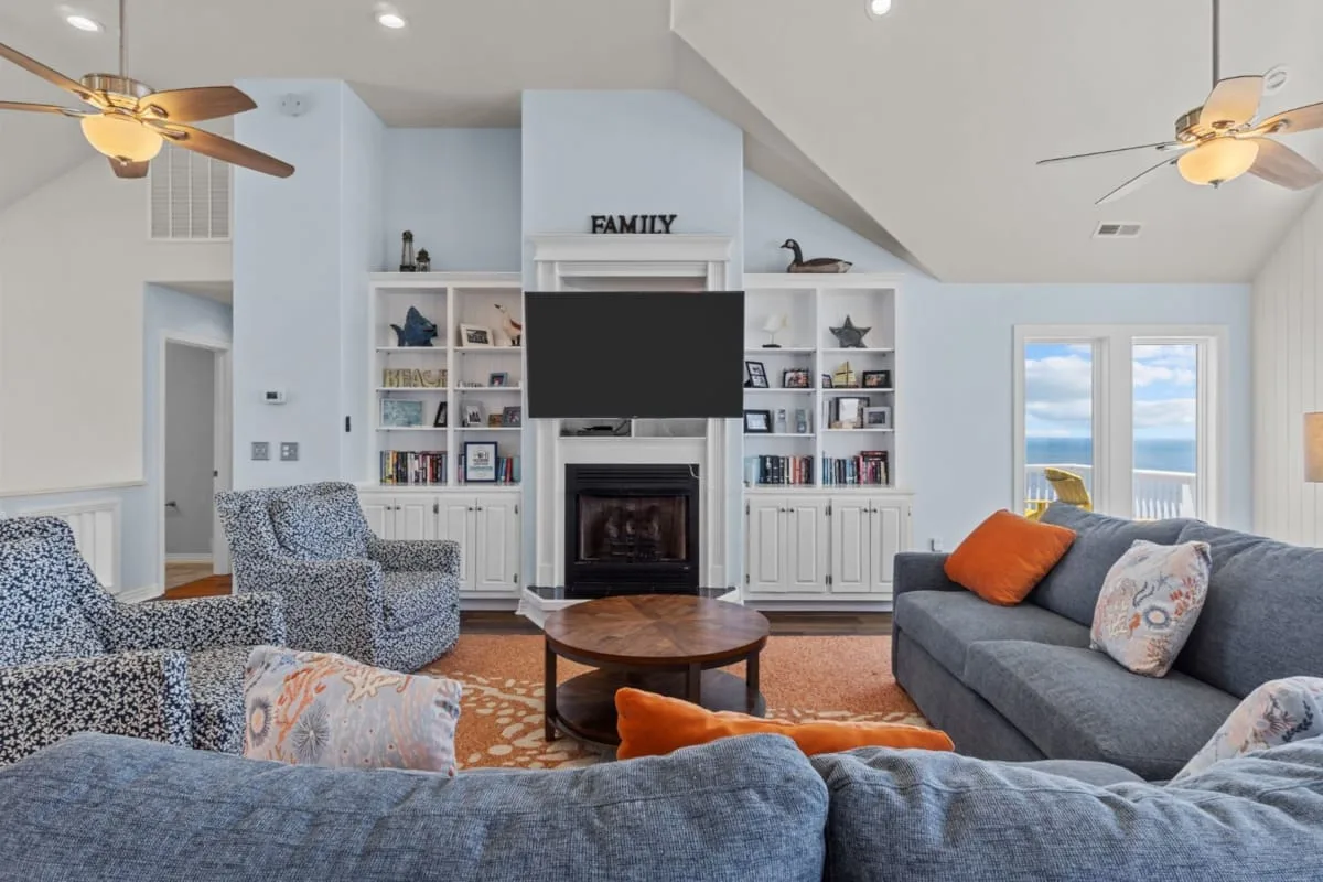 A living room with seating arranged around a fireplace and television.