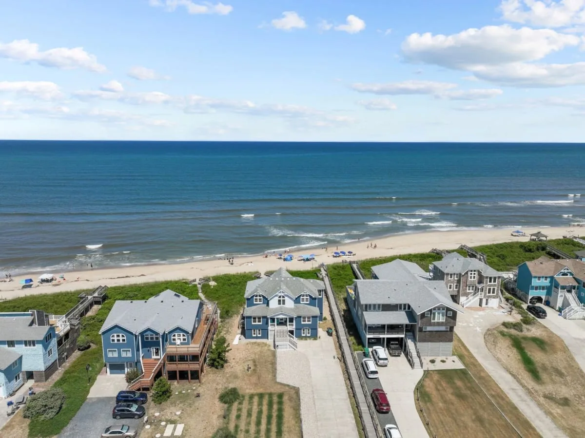 Aerial view of beachfront houses along a sandy shore and ocean.