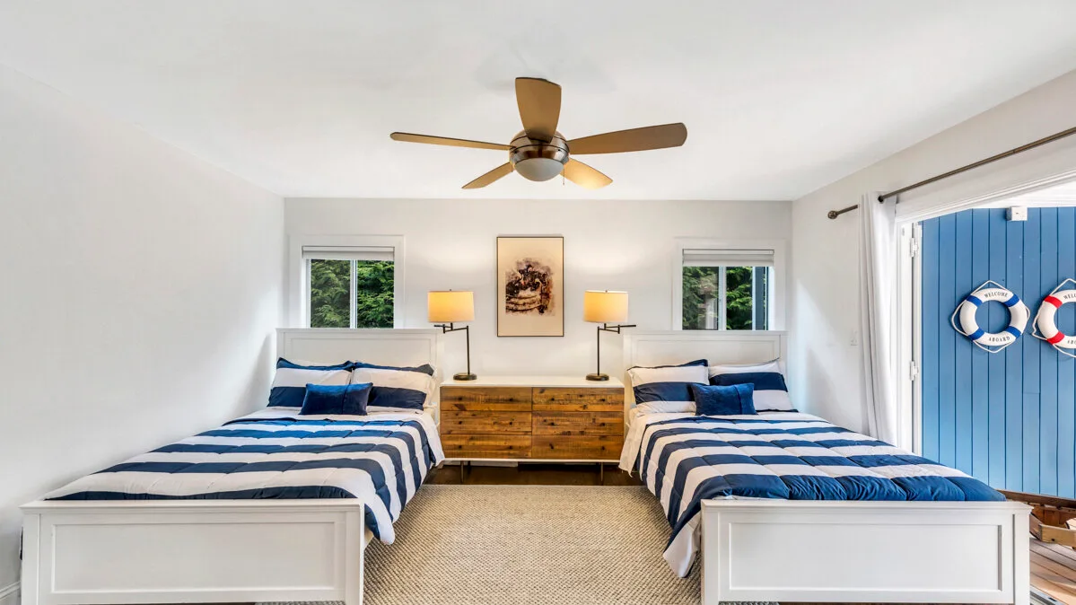 A bright bedroom with two beds dressed in blue-and-white bedding.