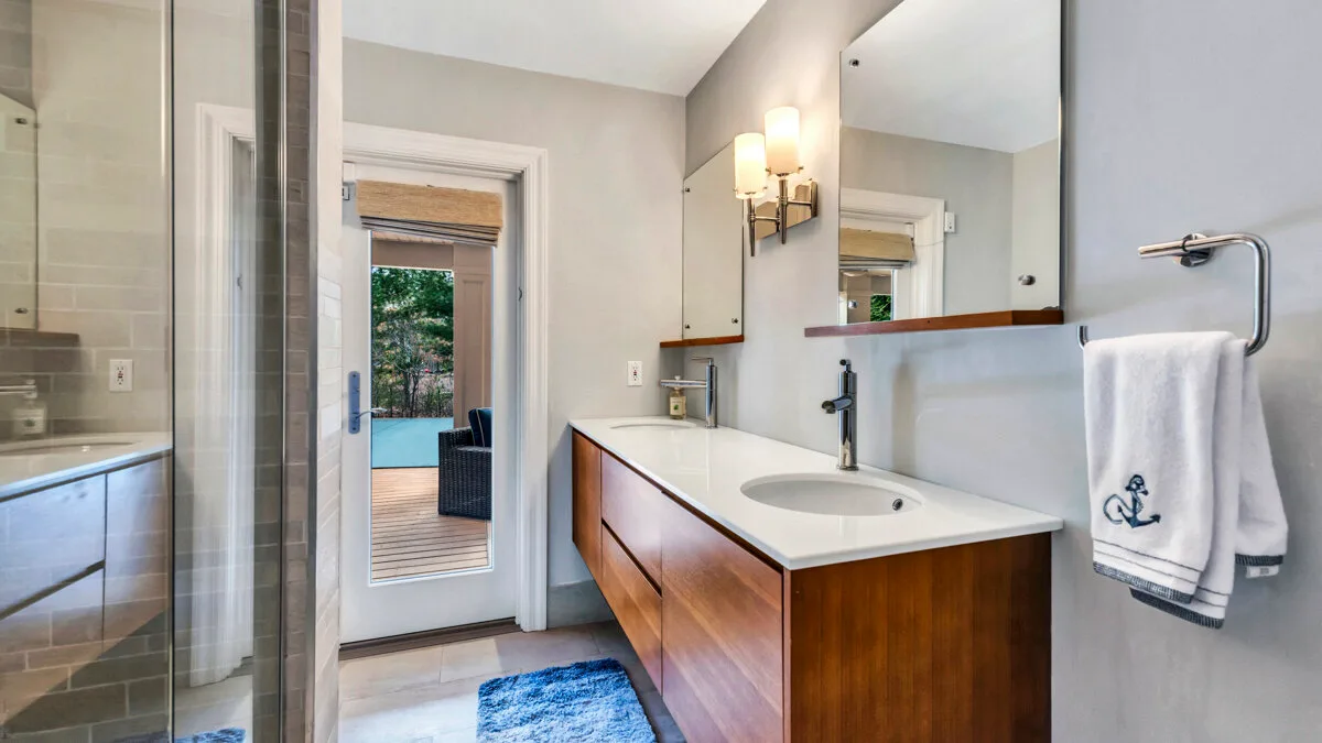 A bathroom with a wooden vanity, sink, and large mirror.