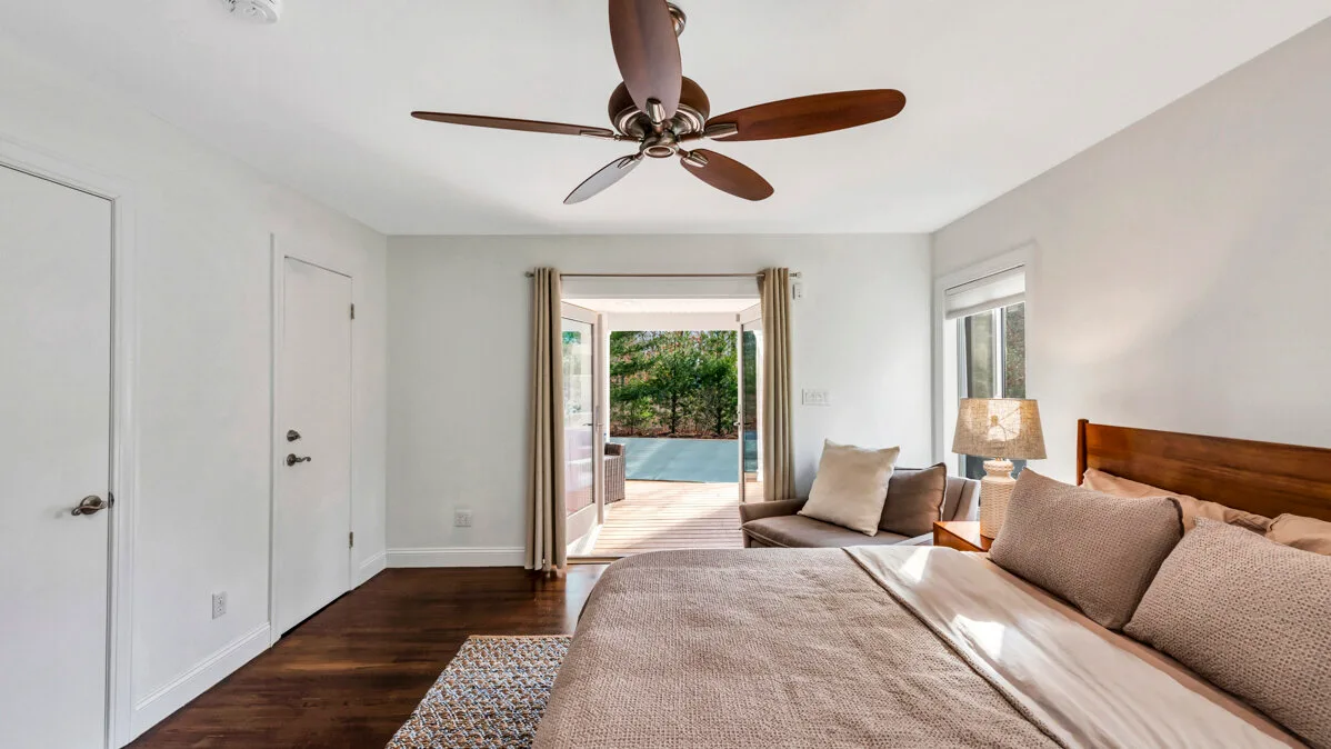 A bright bedroom with a bed, seating, and open doors to a patio.