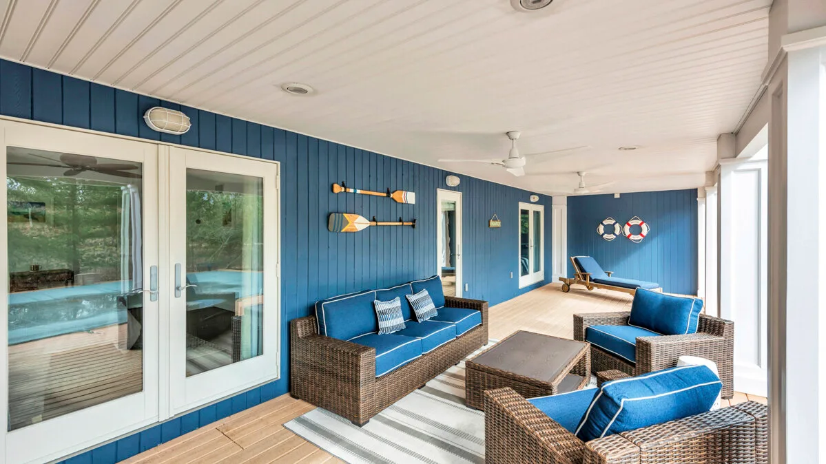 A covered patio seating area with blue cushions and sliding glass doors.