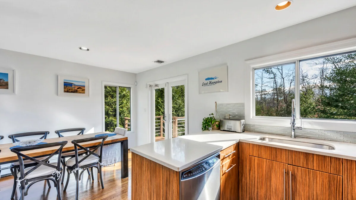 A bright kitchen with wooden cabinets, a white countertop, and a dining table.