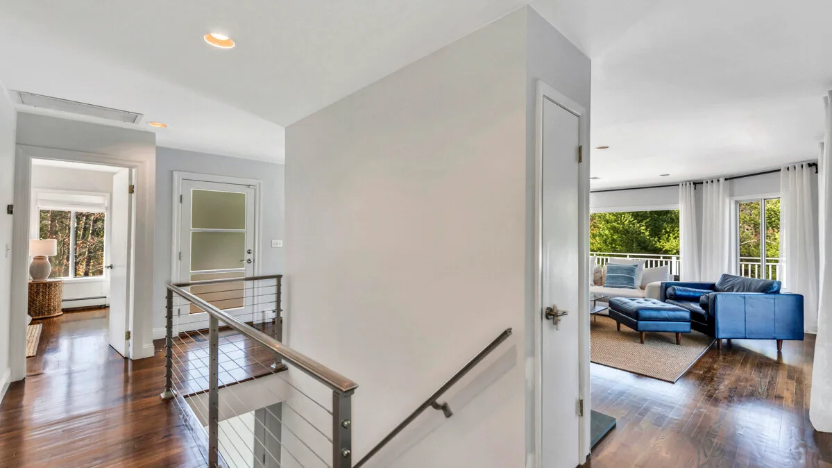A bright interior hallway opens onto a living room with blue seating.