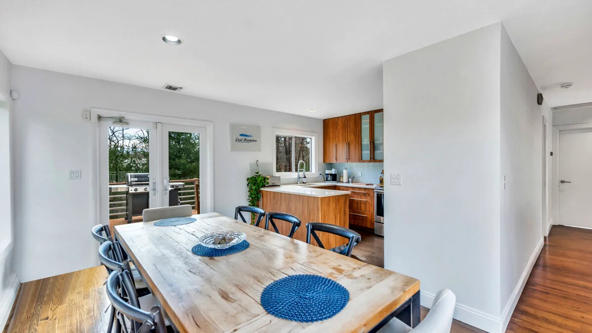 A dining area with a large wooden table beside an open kitchen.