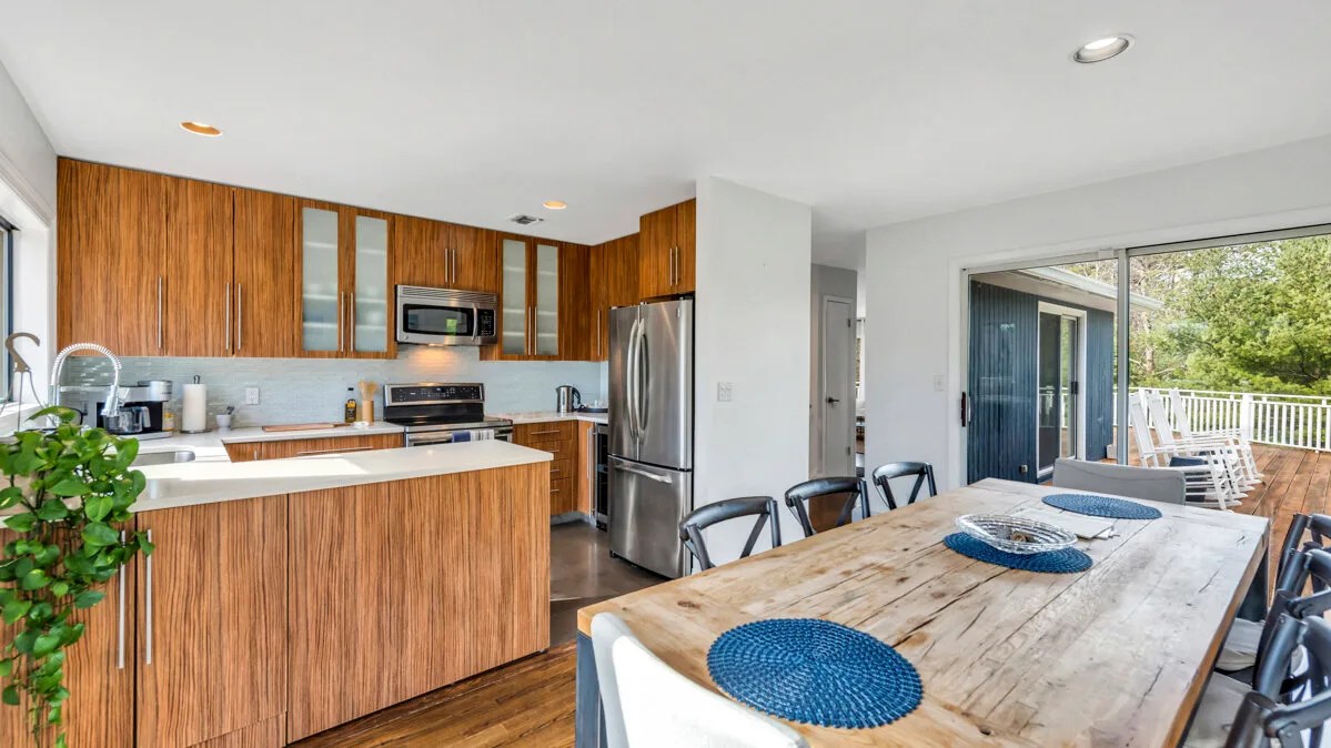 A dining area with a wooden table beside the kitchen and sliding glass doors.