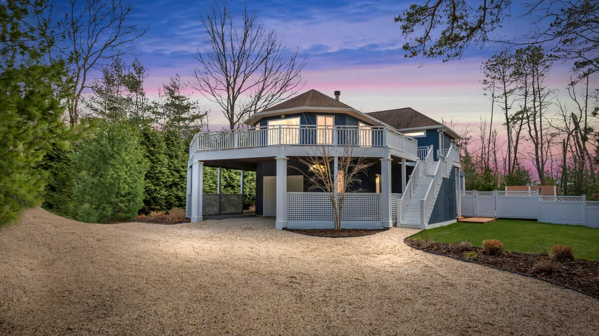 A raised deck and stairs extend from a house into a landscaped yard.