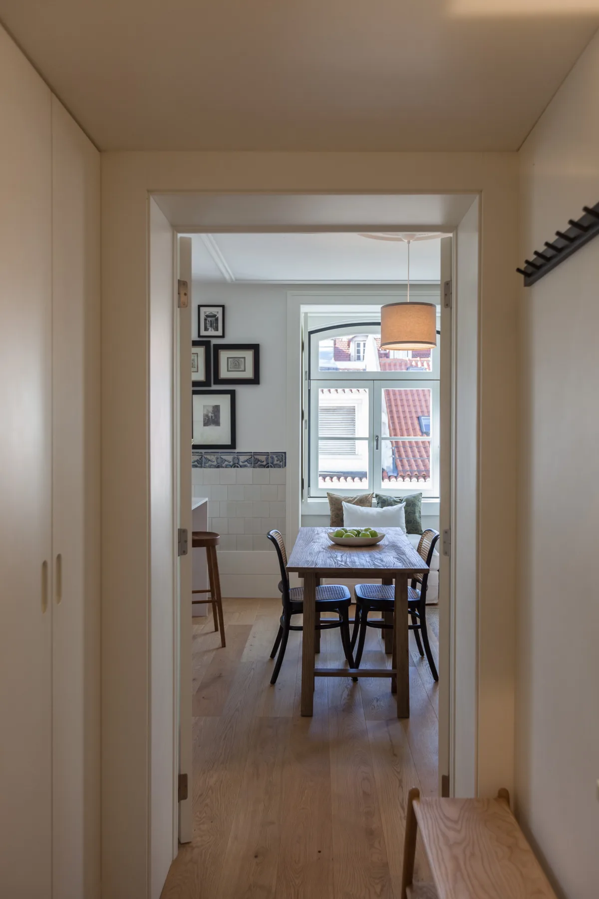A hallway opens onto a dining area with a table beside a window.