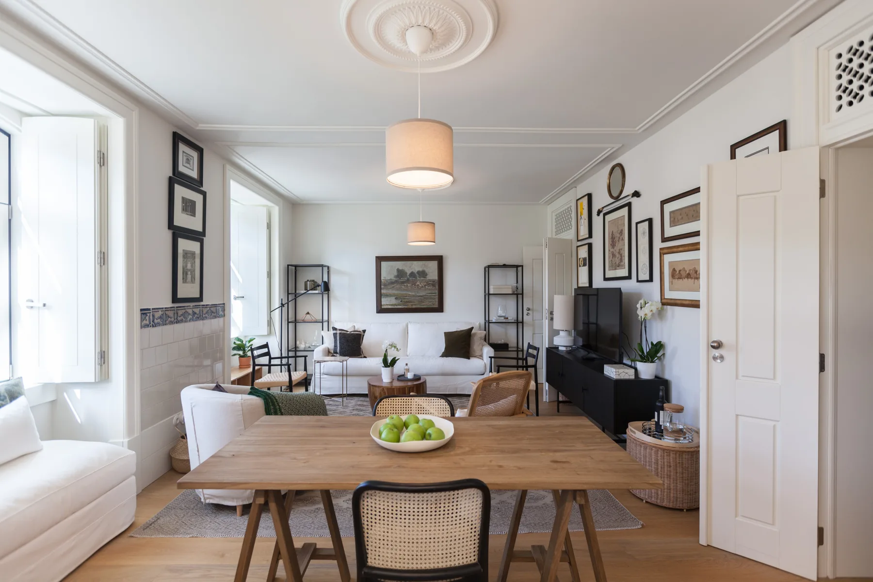 A bright living and dining room with a wooden table and seating.