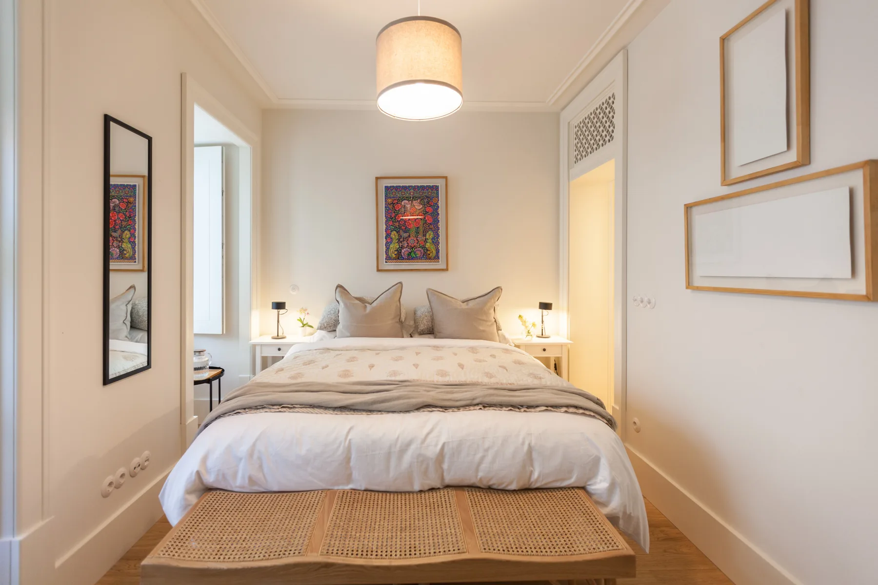 A bedroom with a neatly made bed and framed artwork on the walls.