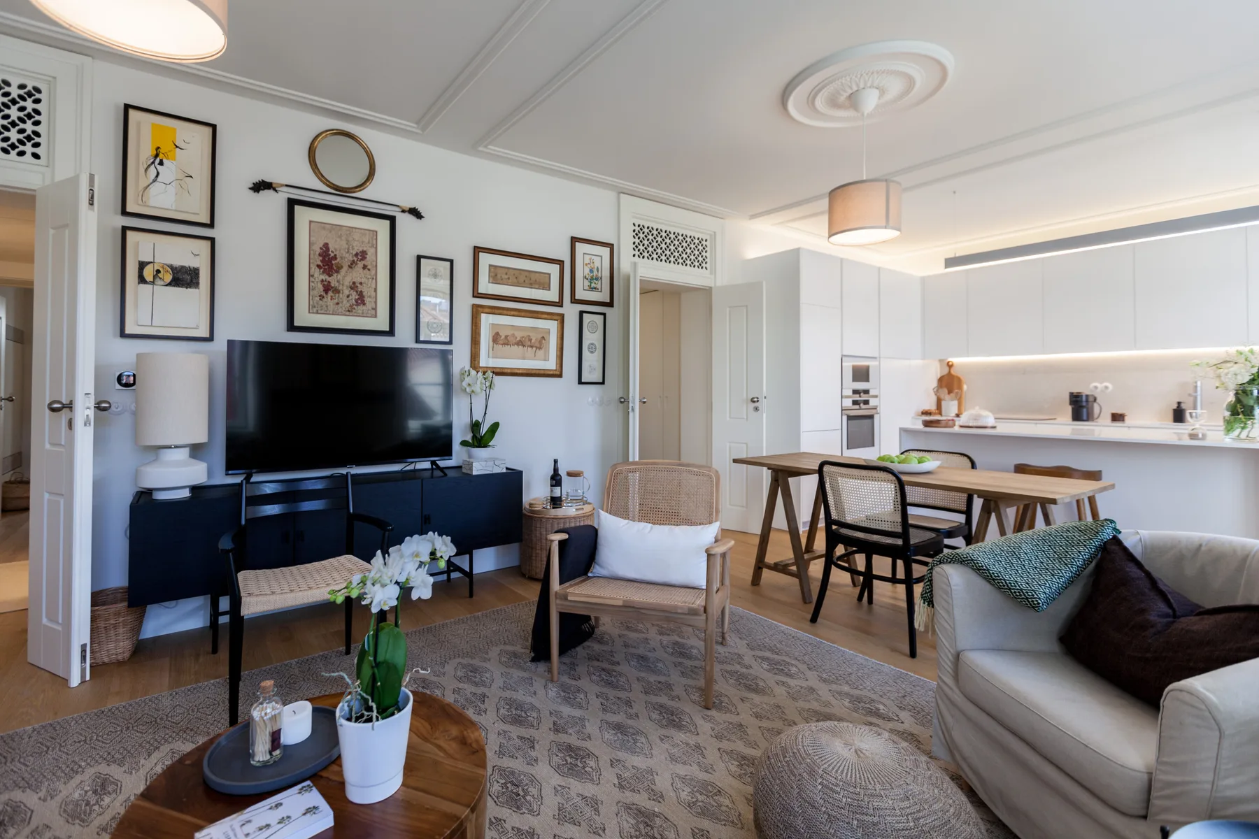 A bright living and dining area with framed artwork and an open kitchen.