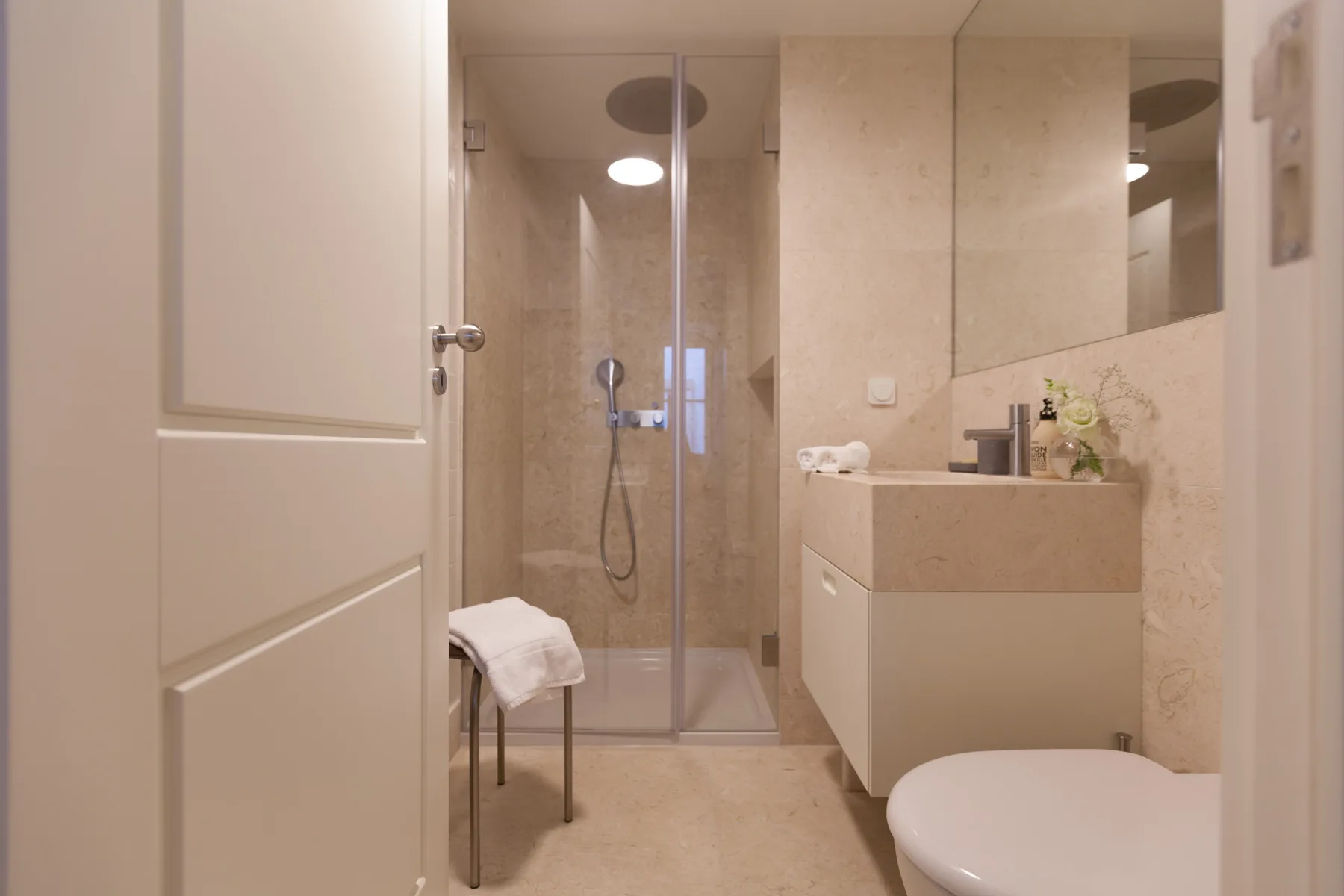 A bathroom with a glass shower, vanity, and toilet.
