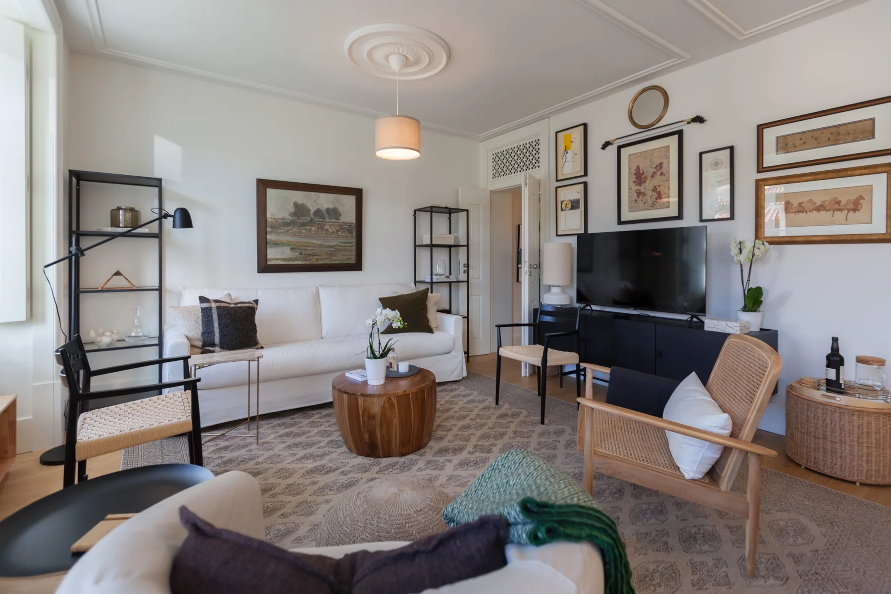 A living room with seating, a television, framed artwork, and a patterned rug.