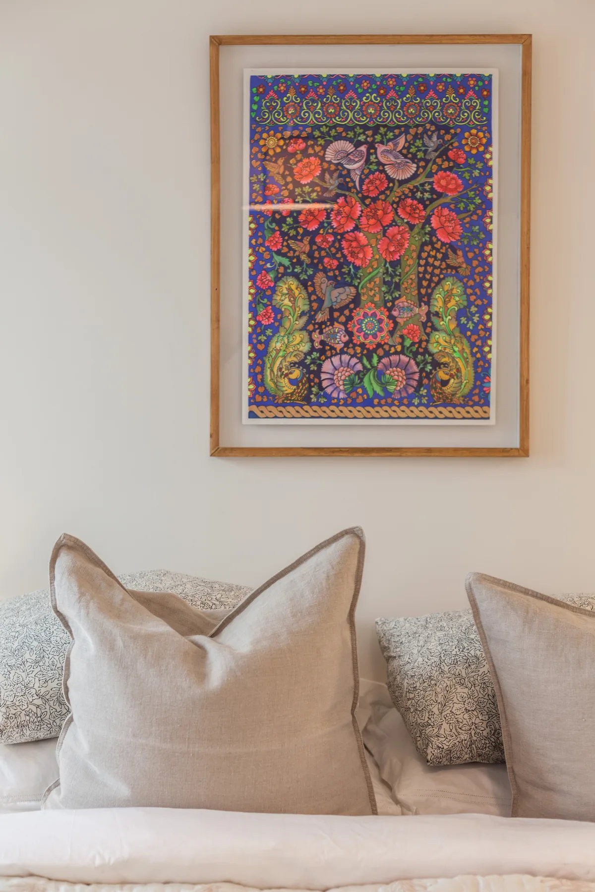 A bedroom seating area with neutral cushions beneath colorful framed artwork.