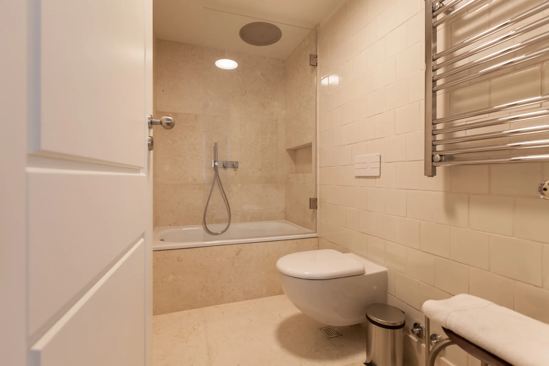 A tiled bathroom with a bathtub, wall-mounted shower, and toilet.
