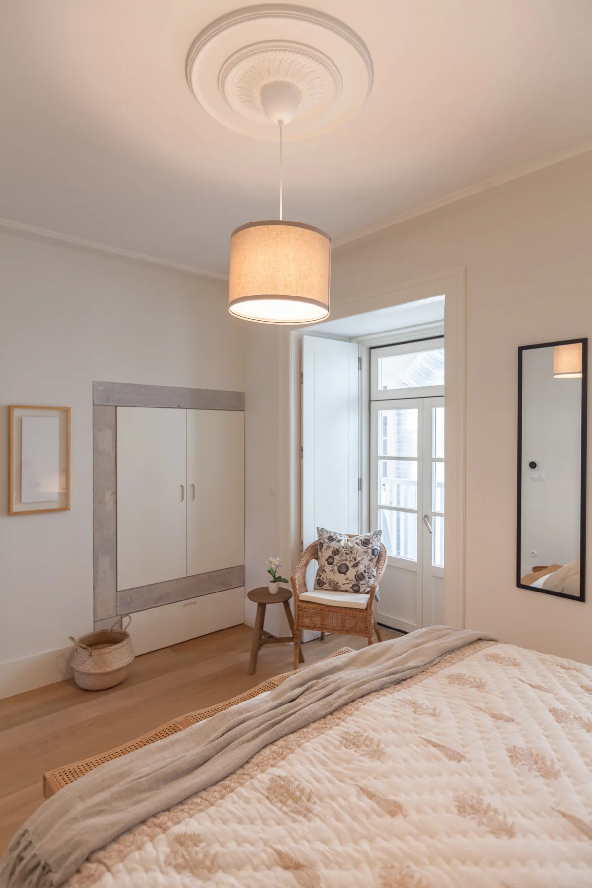 A bedroom with a bed, a chair, and a bright window.