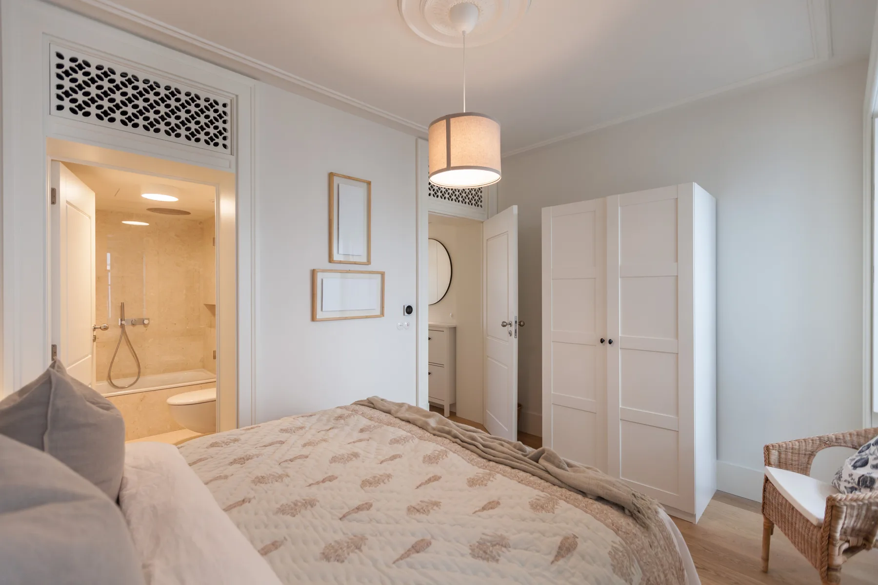 A bedroom with a bed, bedside seating, and an open doorway to a bathroom.