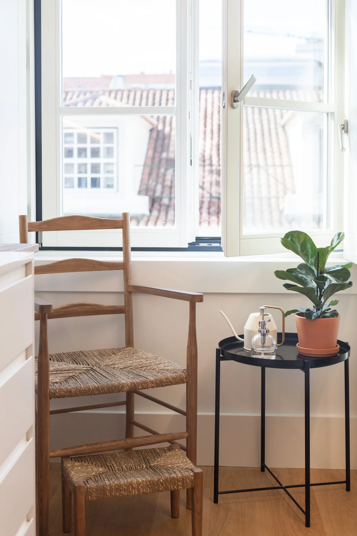 A bright seating nook by a large window, with a wooden chair and potted plant.