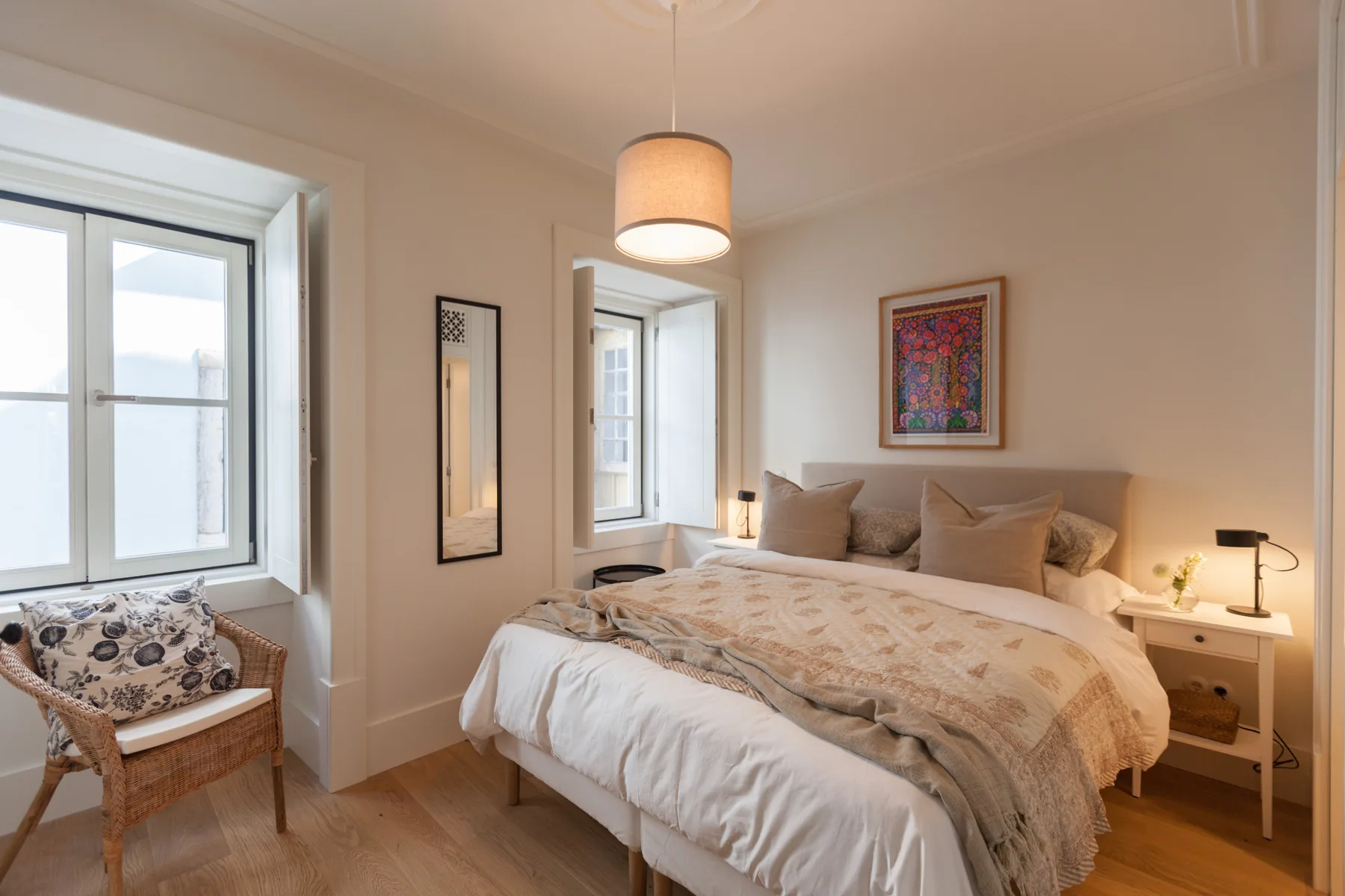 A bedroom with a bed, bedside table, and framed artwork.