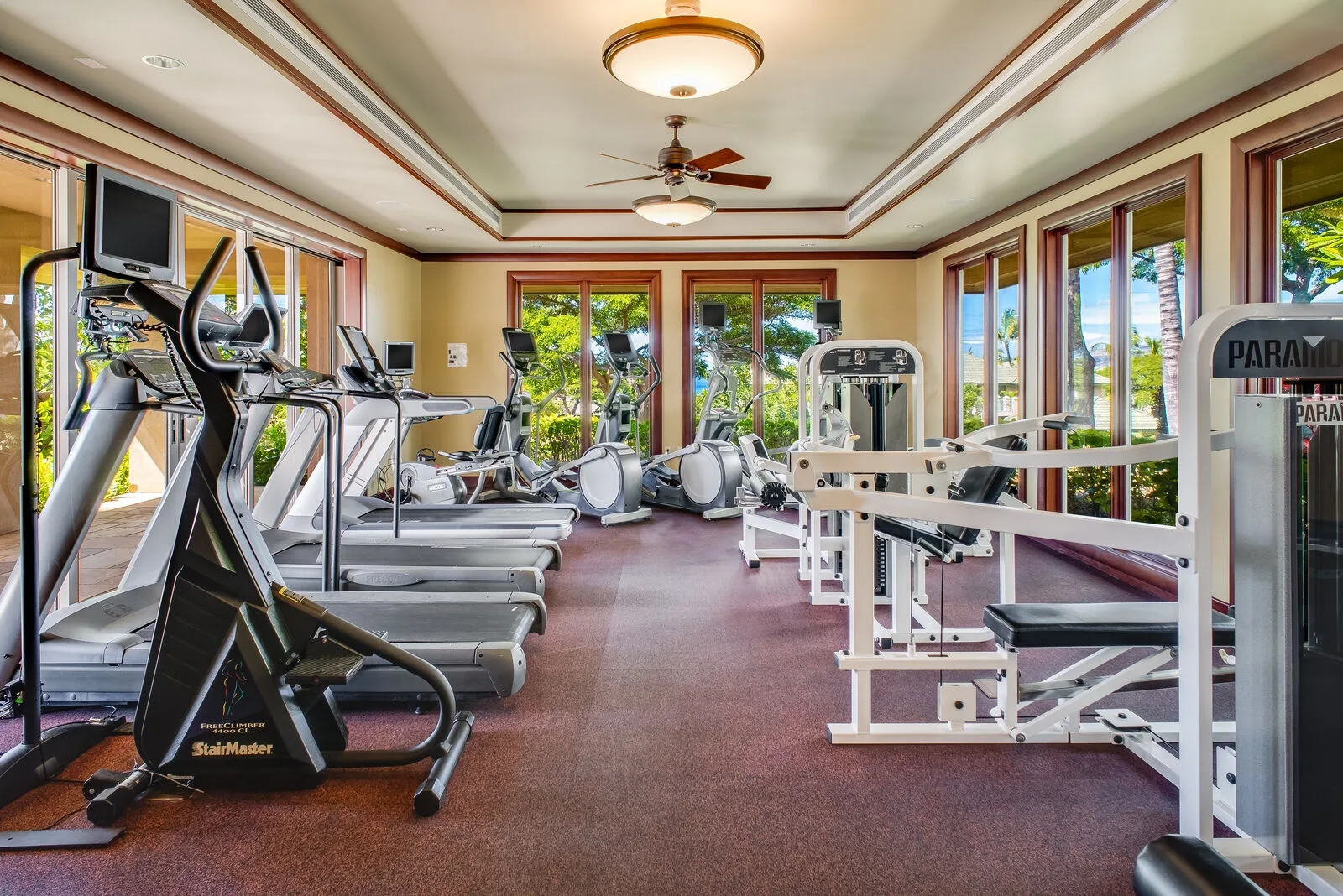 Un gimnasio con máquinas de ejercicio y grandes ventanas.