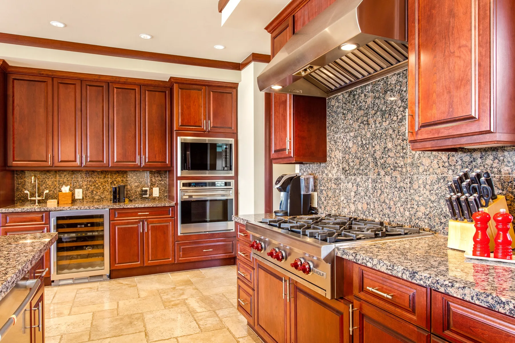 Una cocina con gabinetes de madera, encimeras de piedra y una estufa central.