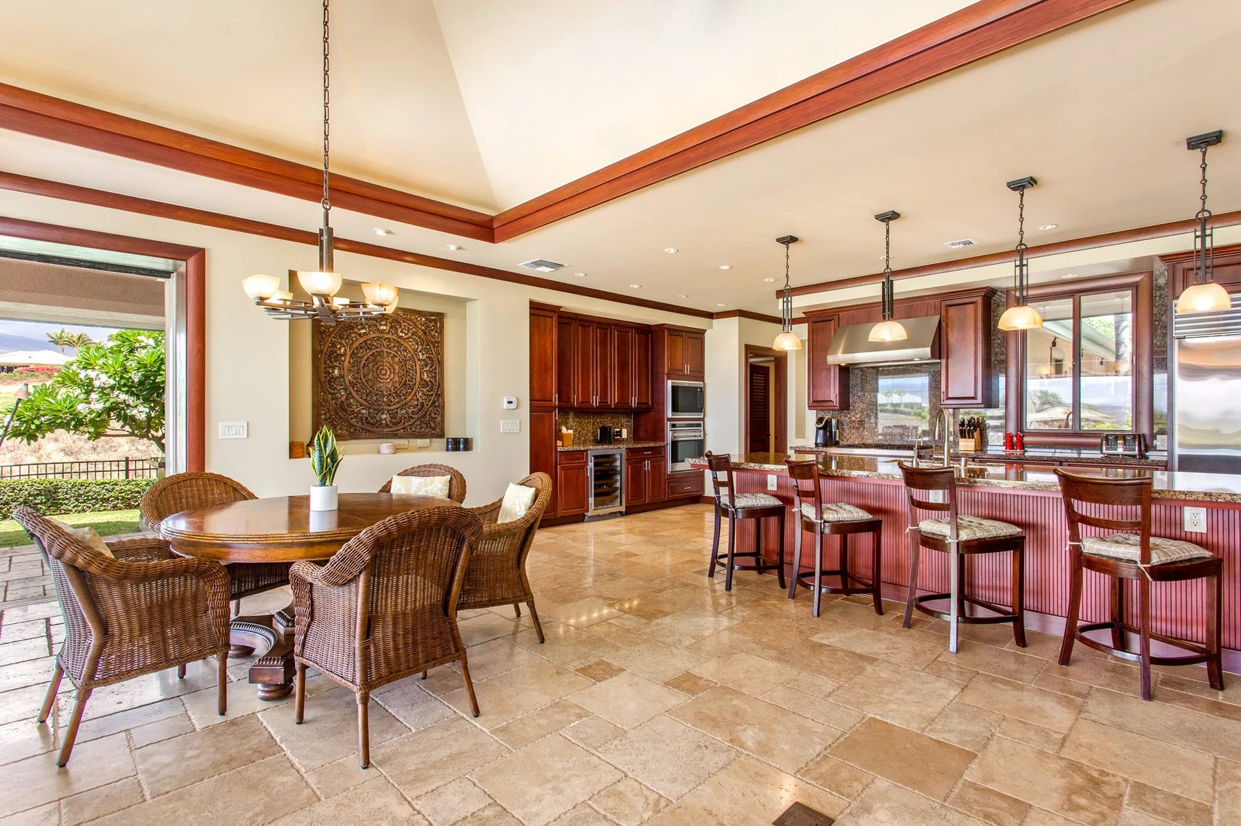 A spacious dining and kitchen area with a table, counter seating, and large windows.