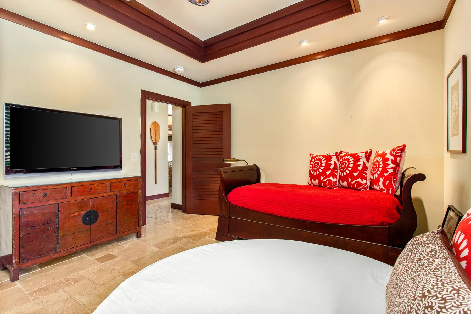 Una sala de estar con un diván rojo y un televisor sobre un mueble de madera.