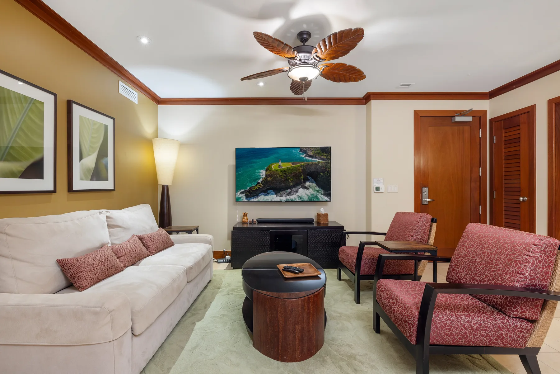 Una sala de estar con asientos, una mesa de centro y un televisor en la pared.