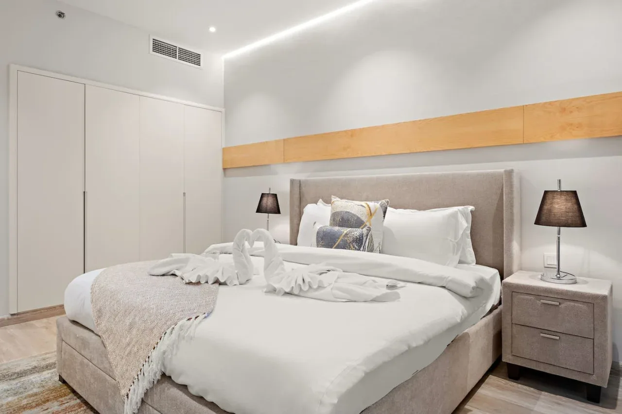 Un dormitorio con una cama bien tendida y lámparas a ambos lados.