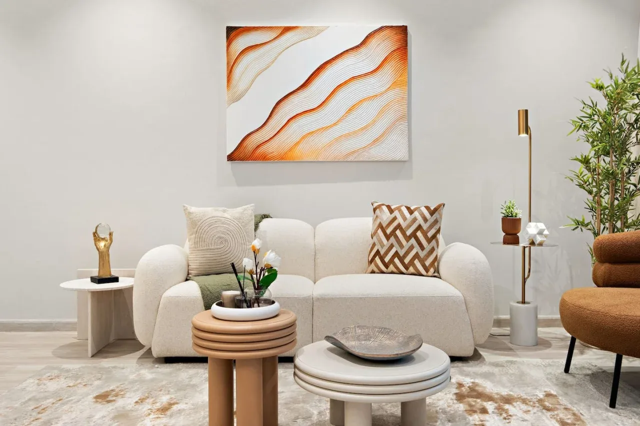 Una sala de estar luminosa con un sofá crema y arte abstracto en la pared.