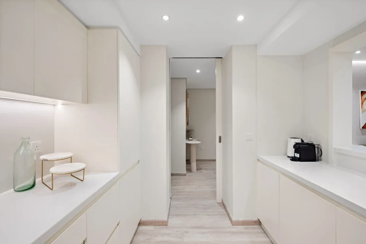 Una cocina moderna y luminosa con encimeras y gabinetes blancos.