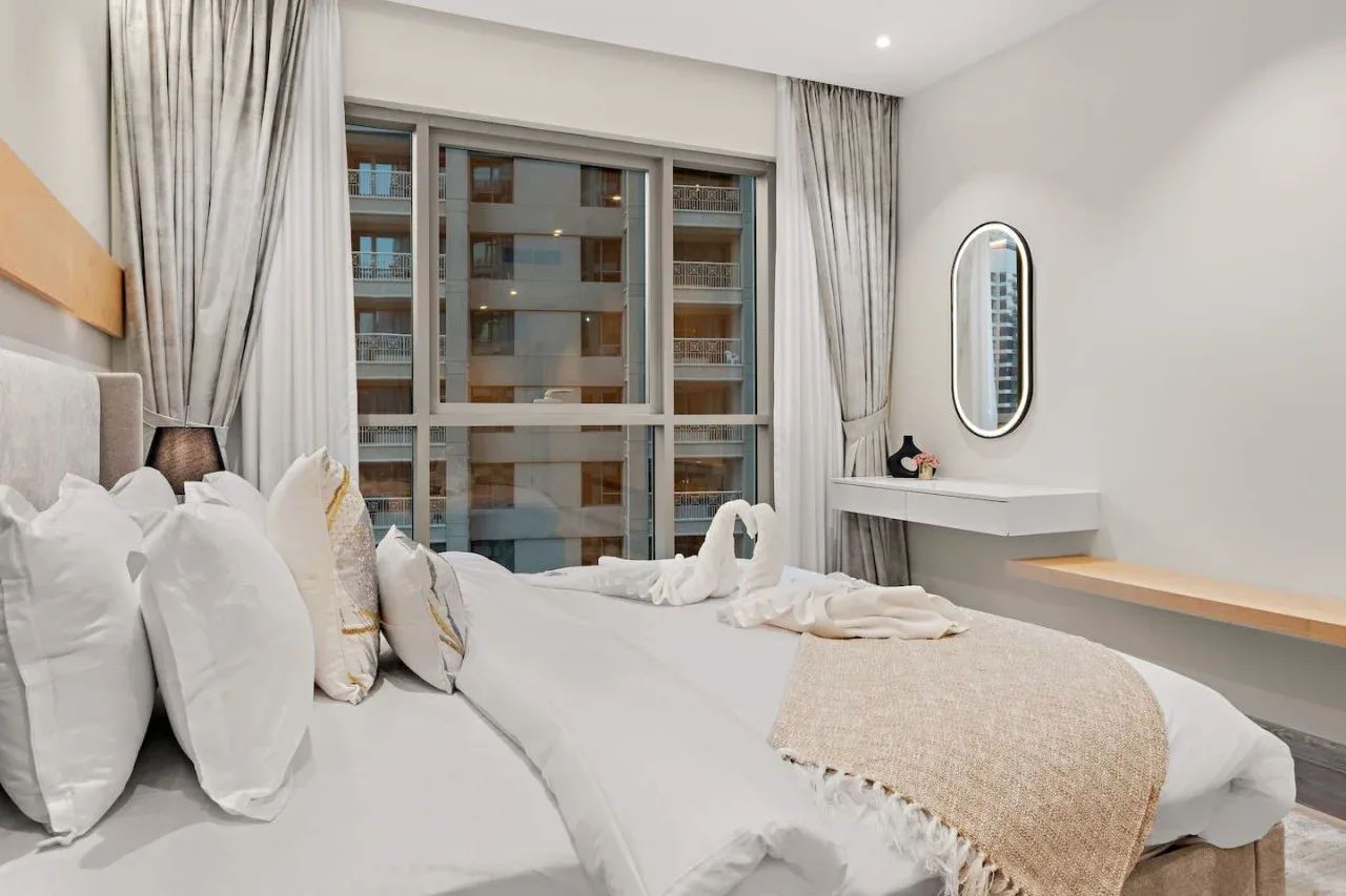 Un dormitorio luminoso con camas bien tendidas y una ventana amplia.