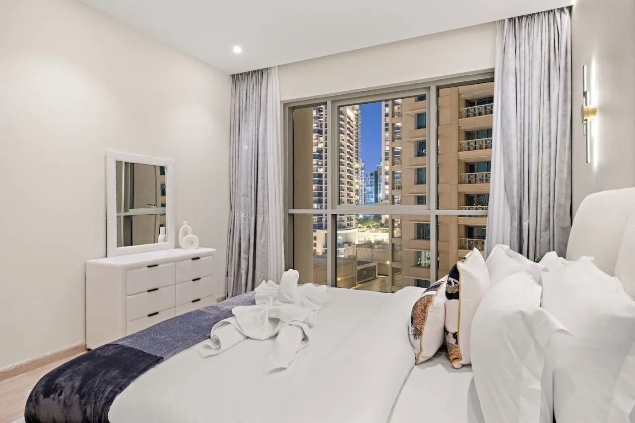 Un dormitorio con una gran ventana que da a edificios cercanos.