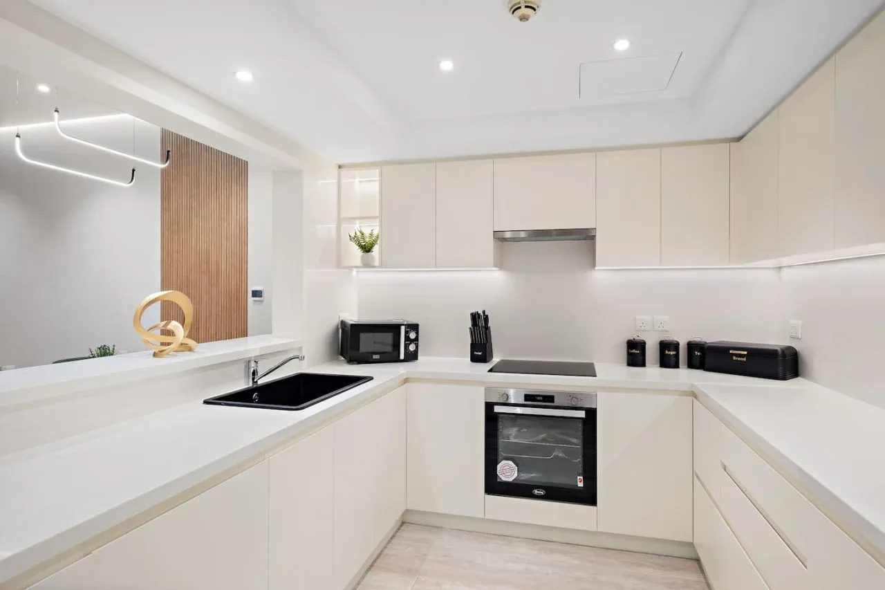 Una cocina moderna y luminosa con gabinetes claros, una placa de cocina y un horno.