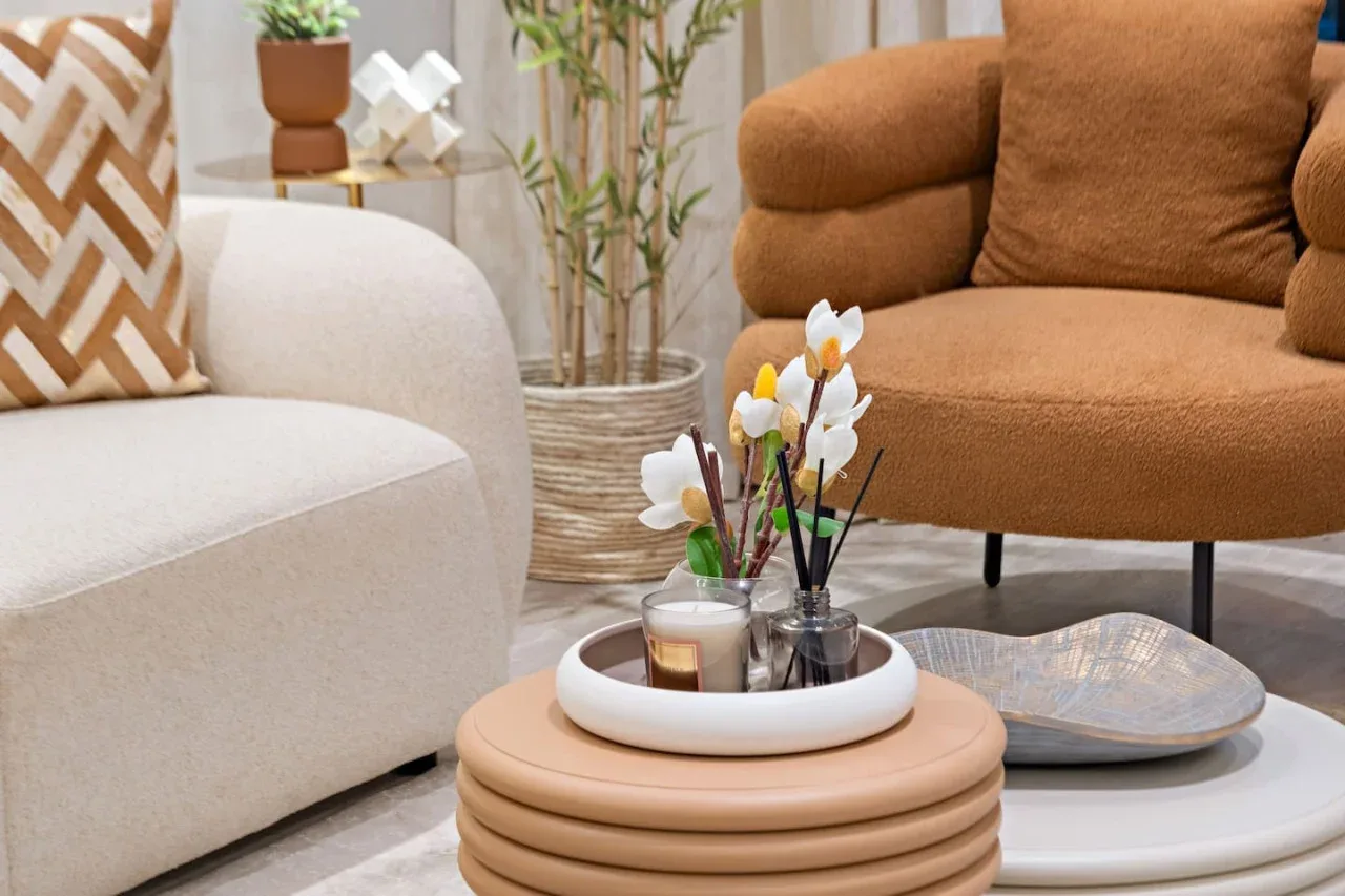 Una zona de estar con flores y velas sobre la mesa de centro.