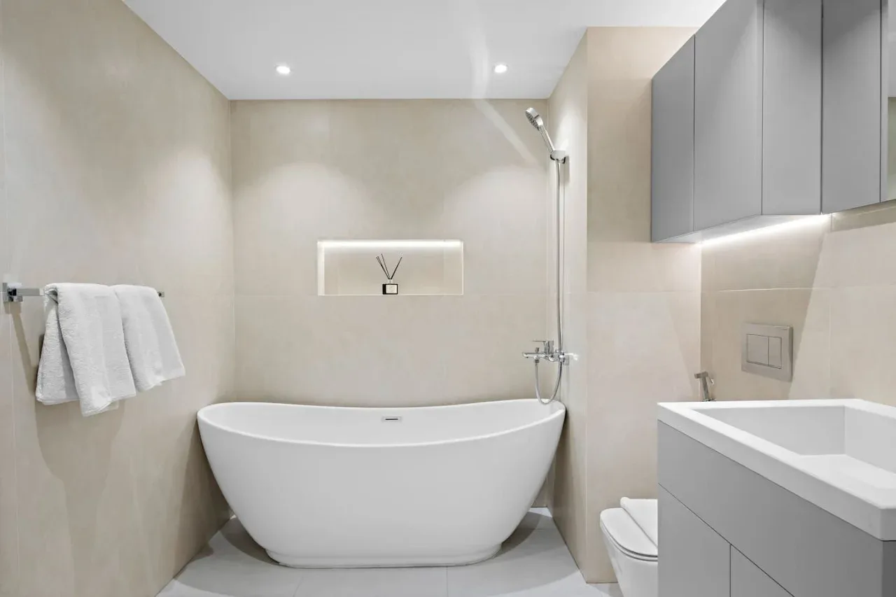 Un baño luminoso con una bañera exenta y un lavabo con mueble.