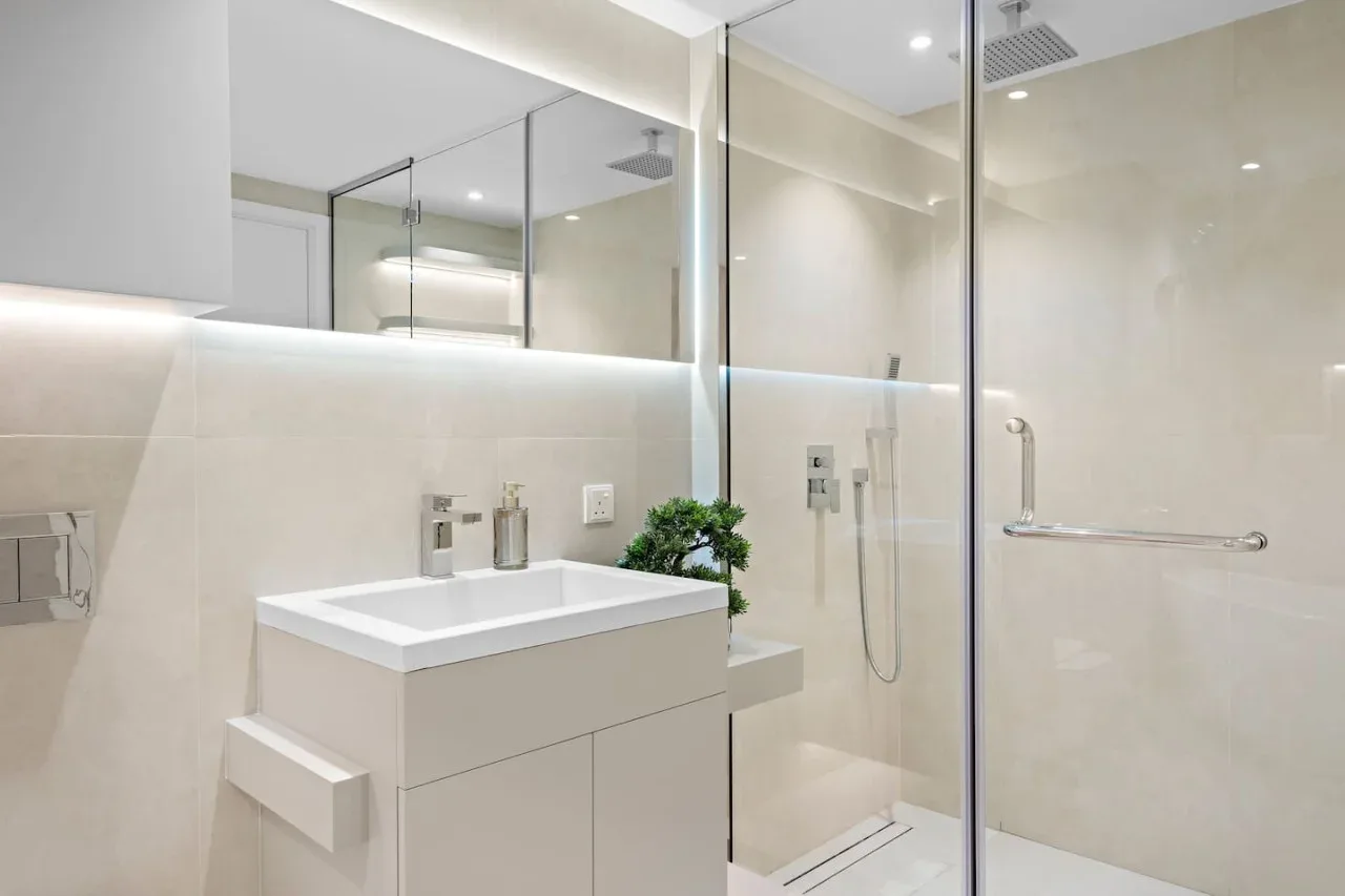 Un baño moderno con lavabo blanco y ducha de vidrio.