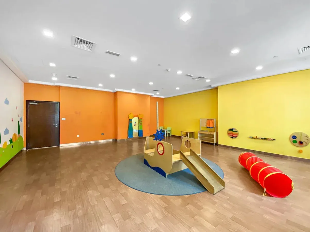 Una sala de juegos interior colorida con un pequeño tobogán y juegos infantiles.