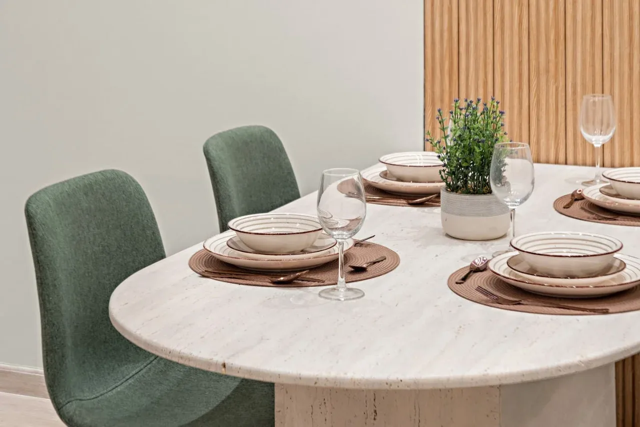 Una mesa de comedor está puesta con platos, copas y una pequeña planta en maceta.