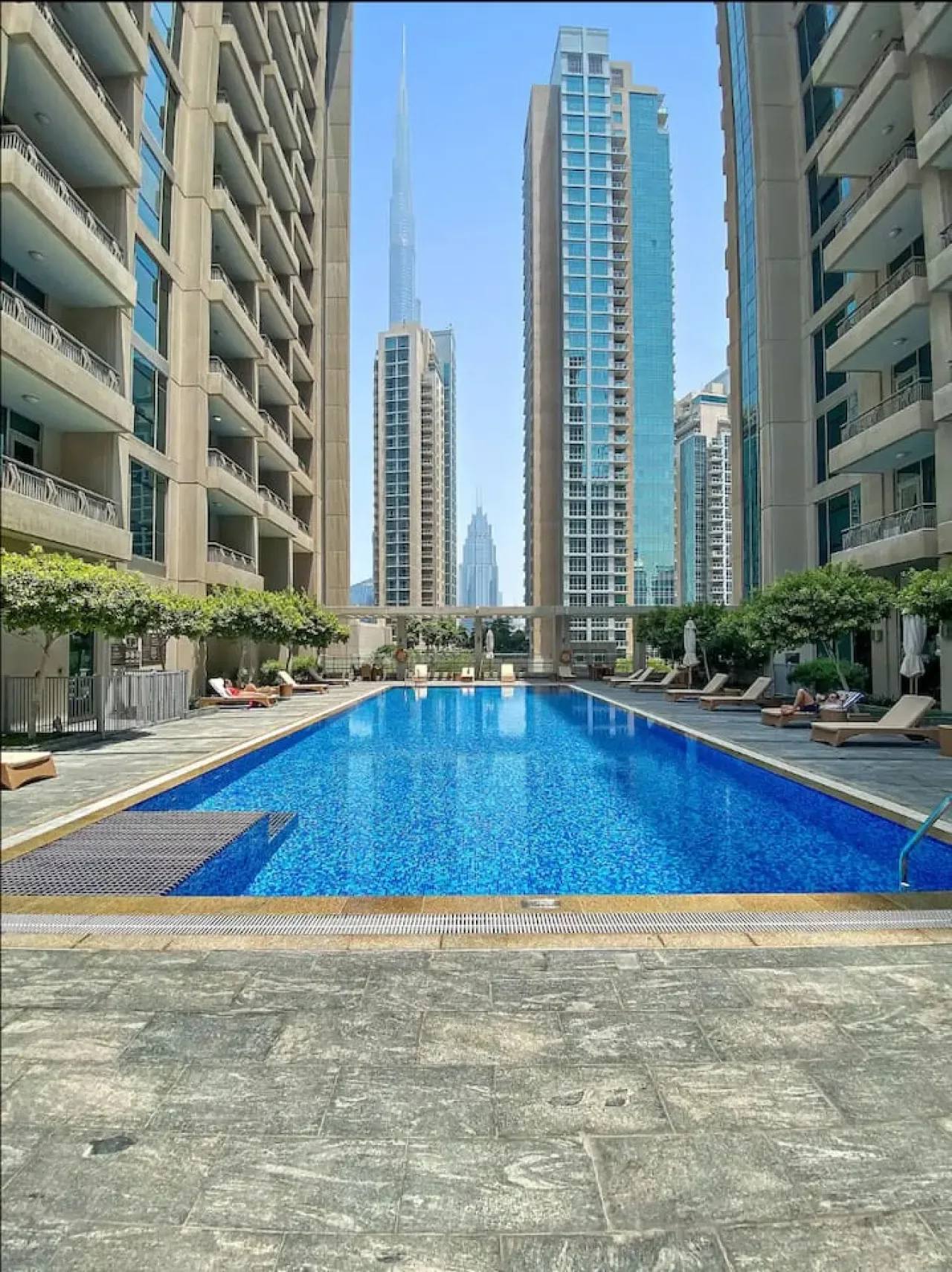 Una piscina al aire libre está entre edificios de apartamentos altos.