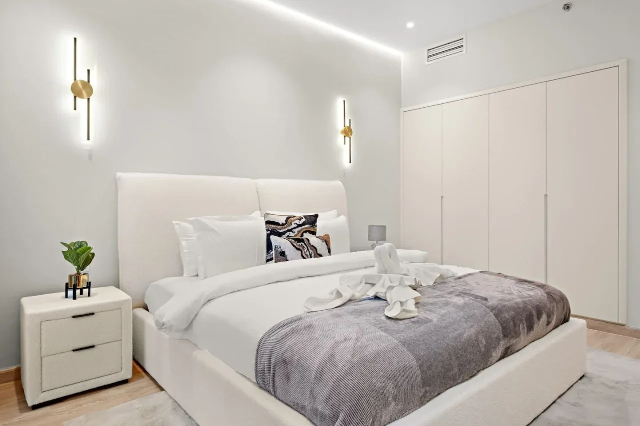 Un dormitorio luminoso con una cama tendida y paredes claras.