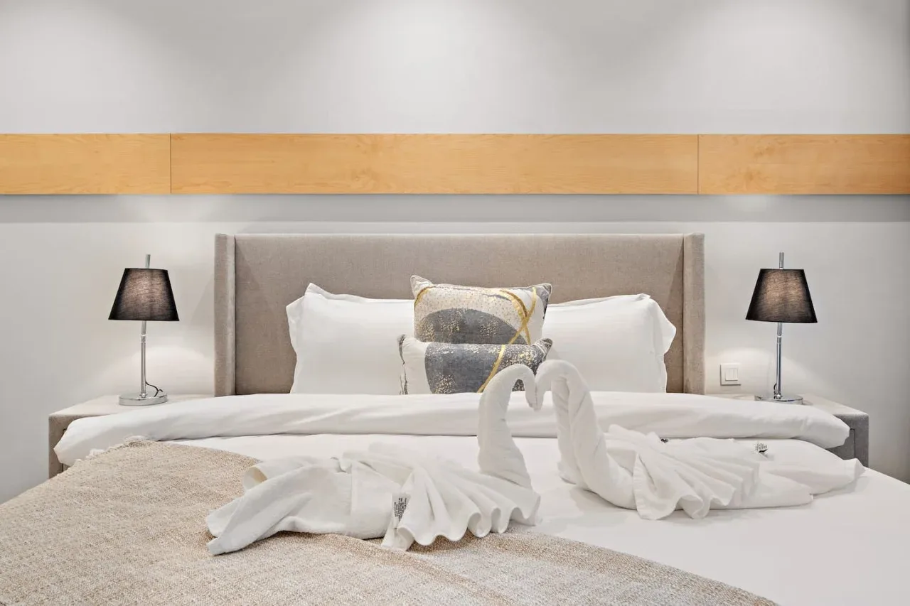 Un dormitorio con ropa de cama blanca y toallas dobladas sobre la cama.
