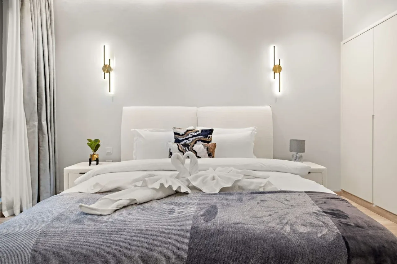 Un dormitorio con una cama tendida y luces de pared a juego.