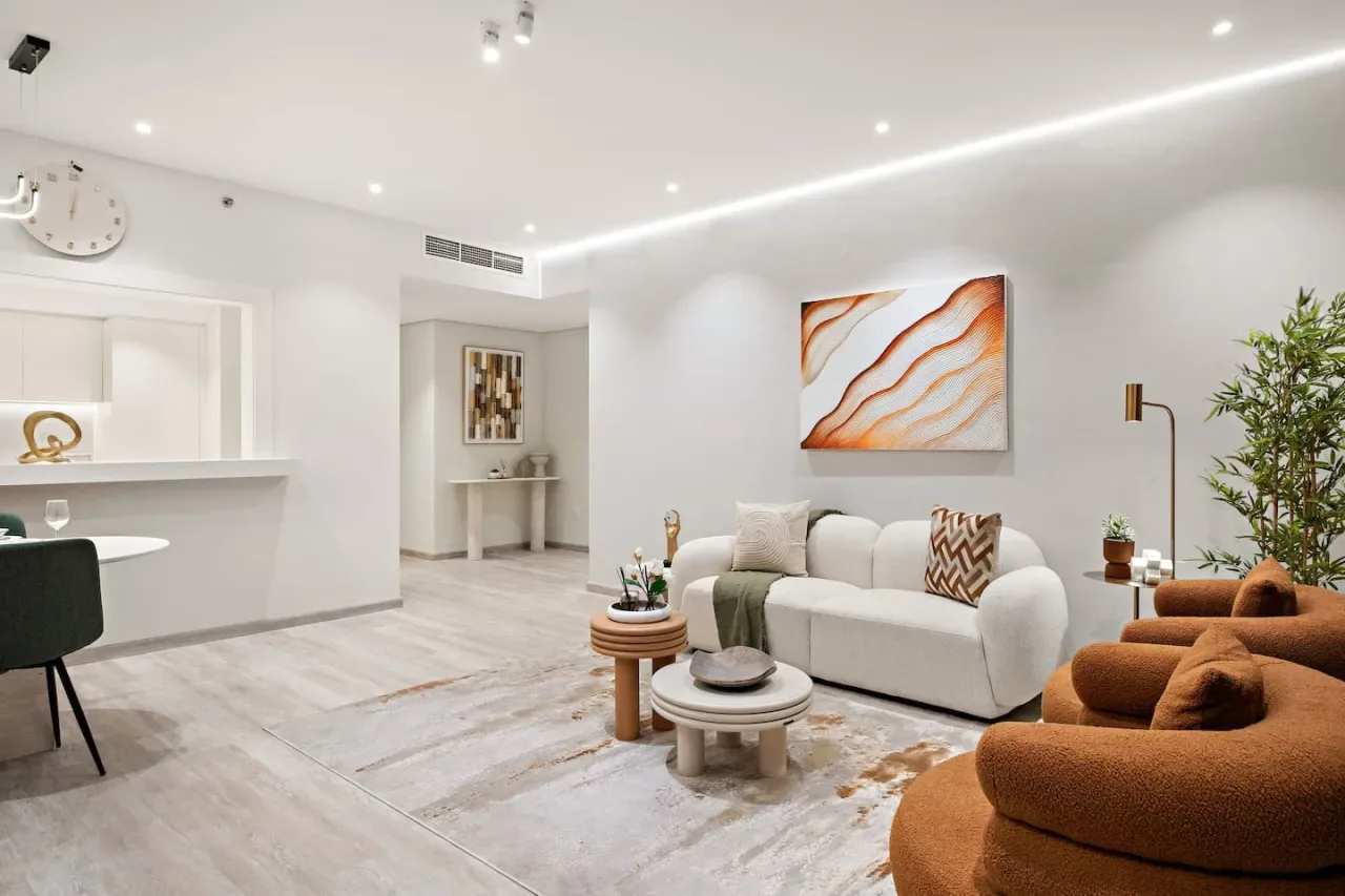 Una sala luminosa con un sofá blanco y arte abstracto en la pared.