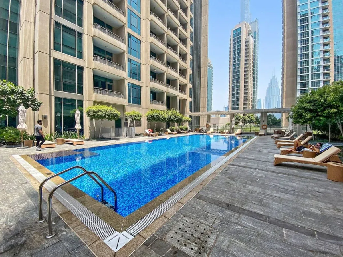 Una piscina en la azotea está rodeada de asientos y edificios altos.
